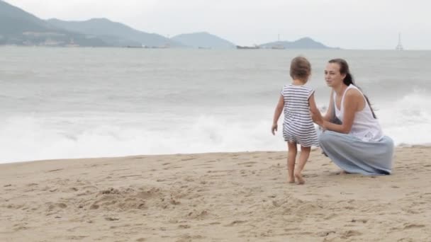 Mutter mit kleiner Tochter läuft bei schlechtem Wetter am Meer entlang — Stockvideo