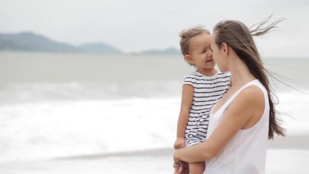 Madre con una hija pequeña en la playa con mal tiempo . — Vídeos de Stock