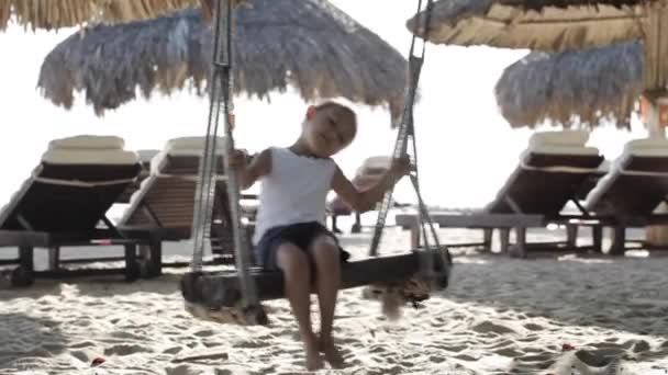 Cute little girl swinging on the sandy beach — Stock Video