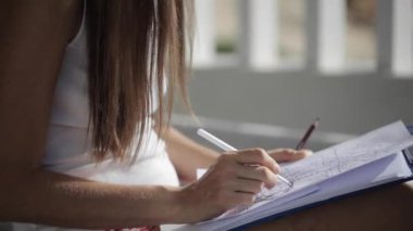 Balkonda oturan ve ballpen ile çizim kağıt üzerinde vakit kadın