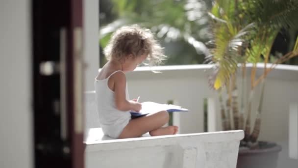 Girl draw by pencil on the paper at balcony with palm trees on the background — Stock Video