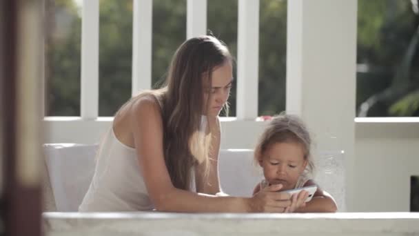 Madre e hija viendo videos divertidos en el teléfono inteligente en el balcón — Vídeos de Stock