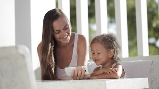 Mãe e filha assistindo vídeo engraçado no smartphone na varanda — Vídeo de Stock