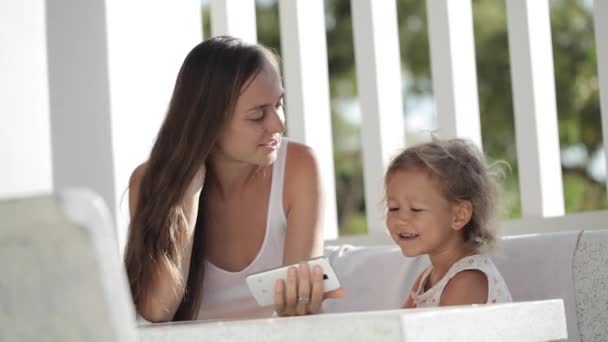 Madre e hija viendo videos divertidos en el teléfono inteligente en el balcón — Vídeos de Stock