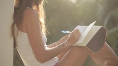 Balkon oturma ve Diary Bahçe ile arka plan üzerinde yazma kadın