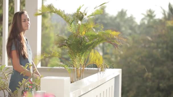 Junge attraktive Frau geht auf die Terrasse und streckt ihre Arme aus — Stockvideo