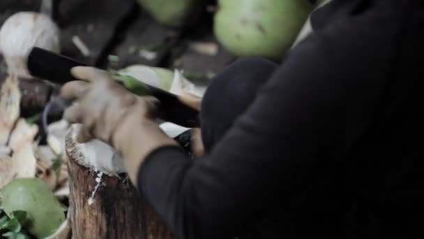 Vânzătorul străzii deschide nuca de cocos cu un cuțit mare . — Videoclip de stoc