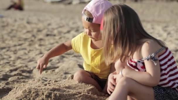 İki küçük sevimli kız sahilde kum ile oynamak — Stok video