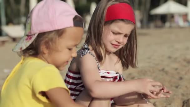 2 つのかわいい女の子がビーチで砂と遊んで — ストック動画