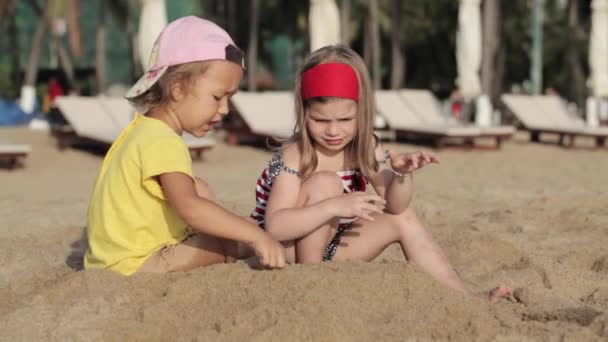 Zwei kleine süße Mädchen spielen mit Sand am Strand — Stockvideo