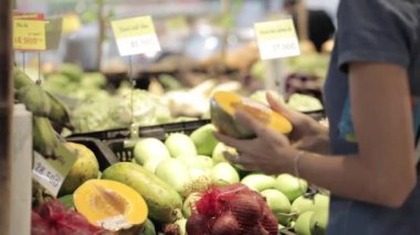 Meyve ve sebze genç çekici kadın bir süpermarkette seçer.