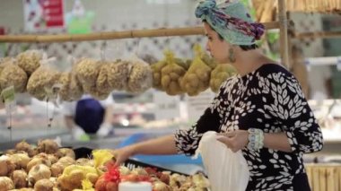 Meyve ve sebze genç çekici kadın bir süpermarkette seçer.