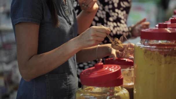 Två unga kvinnans välja kryddor i livsmedelsbutiker avsnitt på stormarknad — Stockvideo