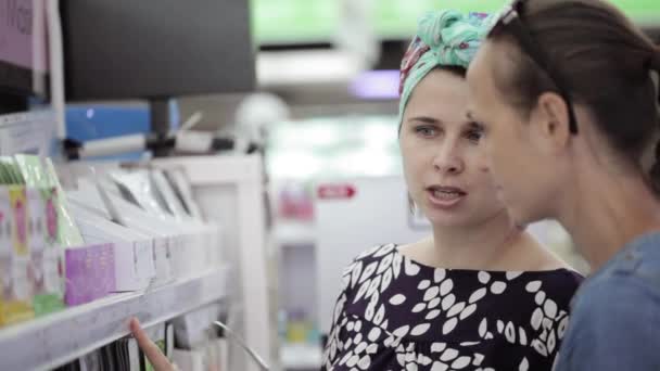 Två attraktiva kvinnans väljer kropp vårdprodukter i stormarknad. — Stockvideo
