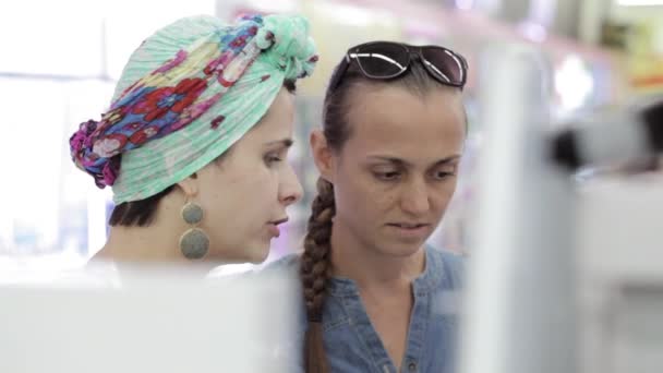 Dos mujeres atractivas eligiendo productos para el cuidado del cuerpo en el supermercado . — Vídeos de Stock