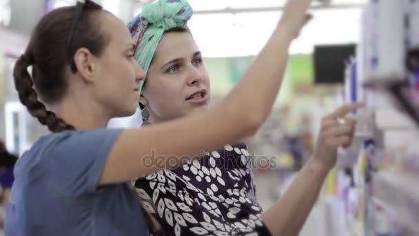 Dos mujeres atractivas eligiendo productos para el cuidado del cuerpo en el supermercado . — Vídeos de Stock