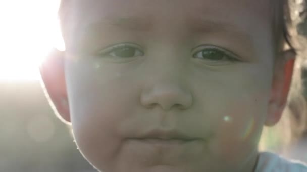 Портрет маленької дівчинки, яка дивиться на камеру на відкритому повітрі, крупним планом — стокове відео