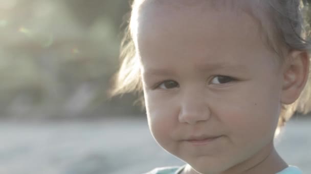 Portrait d'une petite fille regardant la caméra à l'extérieur, gros plan — Video