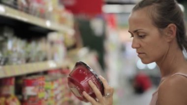 Genç çekici kadın süpermarkette anlık Gıda seçimi