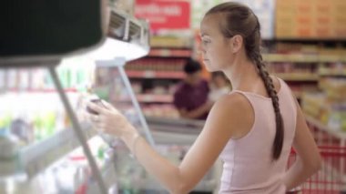 Genç kadın süt gıda buzdolabında bölümünde süpermarkette satın alma