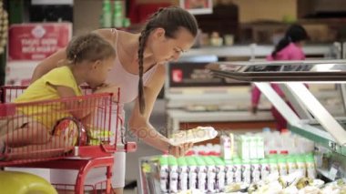 Süpermarkette Dilimleme meyve seçme arabası kızı ile genç anne
