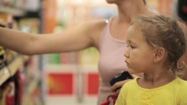 Mãe com pequena filha escolhendo lanches na seção de doces no supermercado — Vídeo de Stock