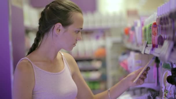 Aantrekkelijke vrouw op zoek lichaamsverzorgingsproducten op cosmetica afdeling in supermarkt — Stockvideo