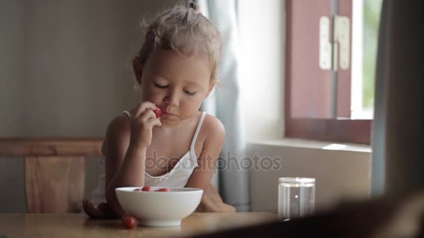 Portret van schattige babymeisje rood cherry tomaat eten — Stockvideo