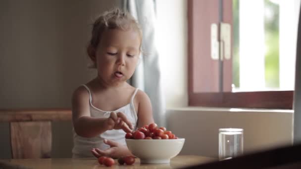 Portrait of cute baby girl eating red cherry tomato — Stock Video