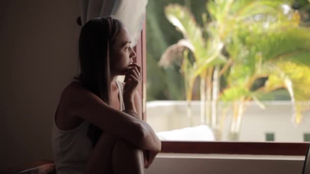 Kaukasiska kvinna sitter och tittar genom fönstret — Stockvideo