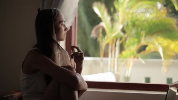 Кавказская женщина сидит и смотрит в окно — стоковое видео