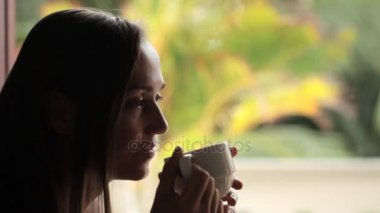 Pencerenin oturan ve çay içme genç çekici kadın