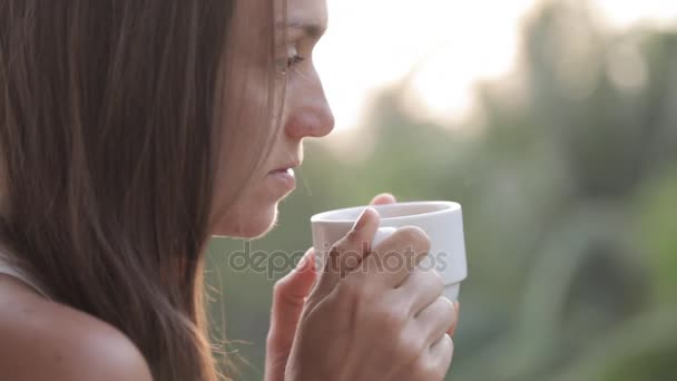 Νέα ελκυστική γυναίκα πίνοντας καφέ ή τσάι στο μπαλκόνι, γκρο πλαν — Αρχείο Βίντεο