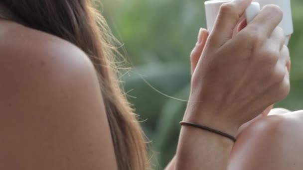 Jonge aantrekkelijke vrouw drinken van koffie of thee op het balkon, close-up — Stockvideo