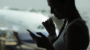 Akıllı telefon kullanarak ve havaalanında abur cubur yeme genç kadın