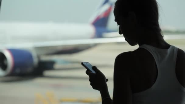 스마트 휴대 전화를 사용 하 고 공항에서 간식 먹는 젊은 여자 — 비디오