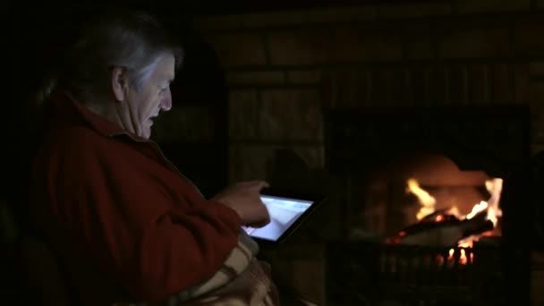 Starší muž sedí u krbu s tabletem a přihlížející rodinné video — Stock video