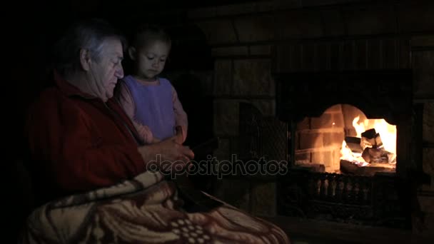 暖炉のそばでタブレットのビデオを見ての孫娘と祖父 — ストック動画