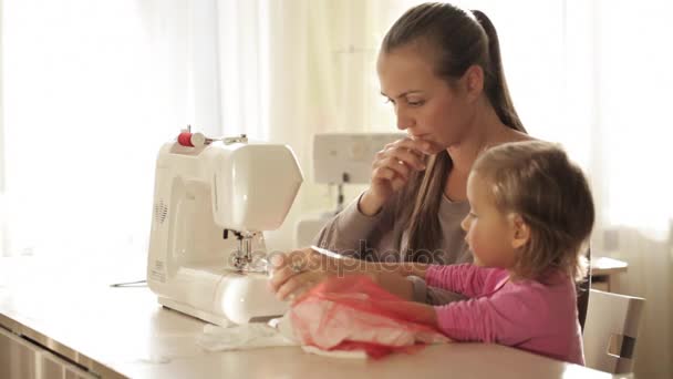 Aantrekkelijke jonge moeder bezig naaimachine met haar kleine schattige dochter — Stockvideo