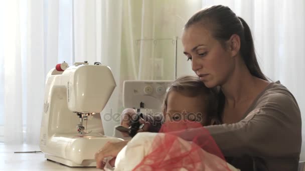 Joven madre atractiva trabajando en la máquina de coser con su pequeña hija linda — Vídeos de Stock