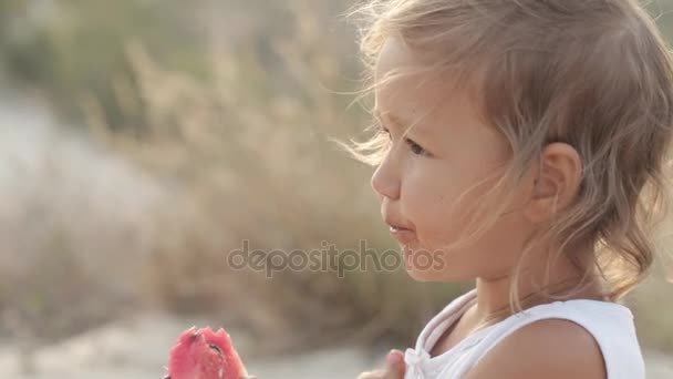 Close-up πορτρέτο της μικρό χαριτωμένο κοριτσάκι τρώνε κόκκινο καρπούζι στο sunrise — Αρχείο Βίντεο