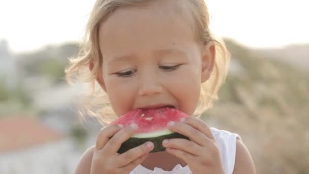 Närbild porträtt av små söta baby flicka äter röd vattenmelon på sunrise — Stockvideo
