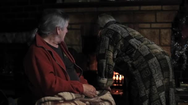 Seniorenpaar sonnt sich am Kamin — Stockvideo