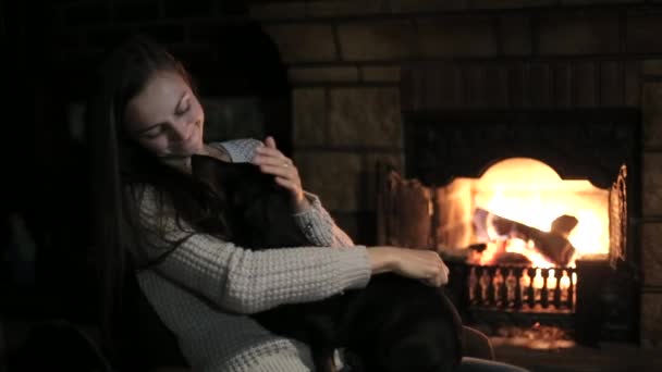 Jeune femme assise devant la cheminée avec chien — Video