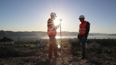 Dağın tepesinde jeodezik ölçümleri performans kask içinde iki sörveyörler