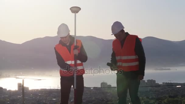 Dois topógrafos vestindo colete laranja apreciando seu trabalho — Vídeo de Stock