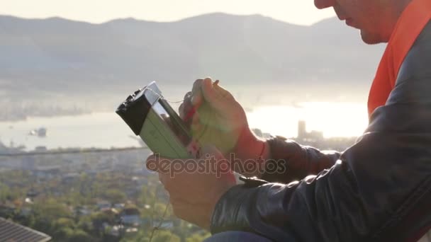 Kaukasiska man i väst och hjälm som sitter på marken på hans utomhus arbetsplats — Stockvideo