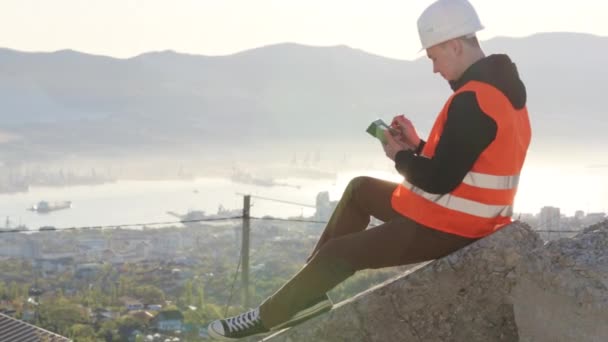 Homme arpenteur assis sur le béton à son lieu de travail extérieur contre du soleil — Video