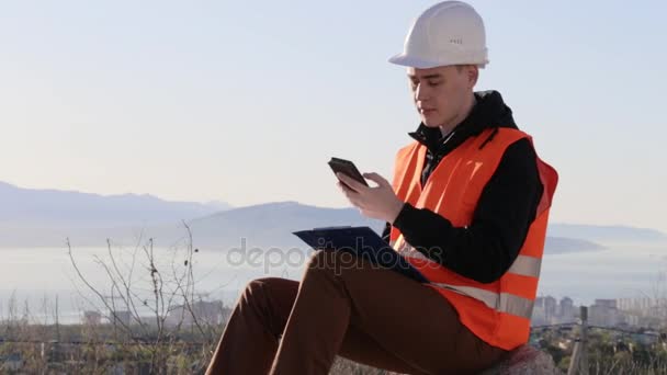 Constructor answering calling of mobile phone drawing lines at workplace — Stock Video