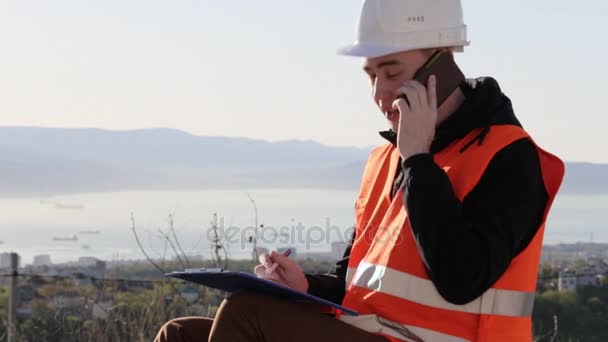 Surveyor svara mobiltelefon ritade linjerna på arbetsplatsen, Utomhus — Stockvideo